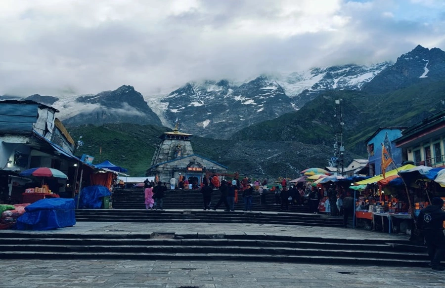 Old image of Kedarnath temple with cloudy atmosphere and snow covered mountains in the background